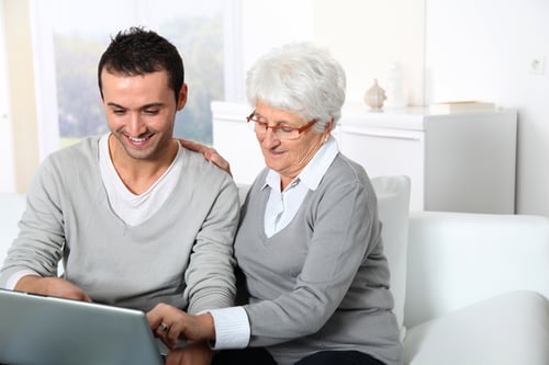 Elderly woman with young man using internet at home
